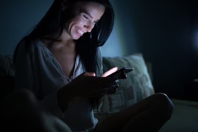 a happy woman is checking her smartphone at night