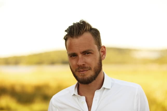 a handsome young man in a white shirt posing outdoors