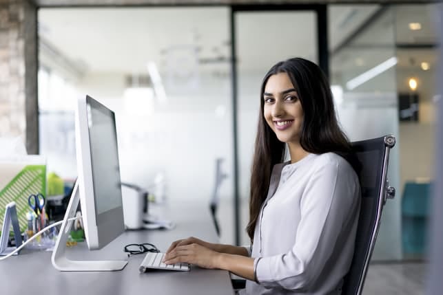 a modern Indian woman is smiling while working at the office