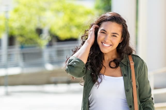a young hispanic woman posing outdoors while smiling