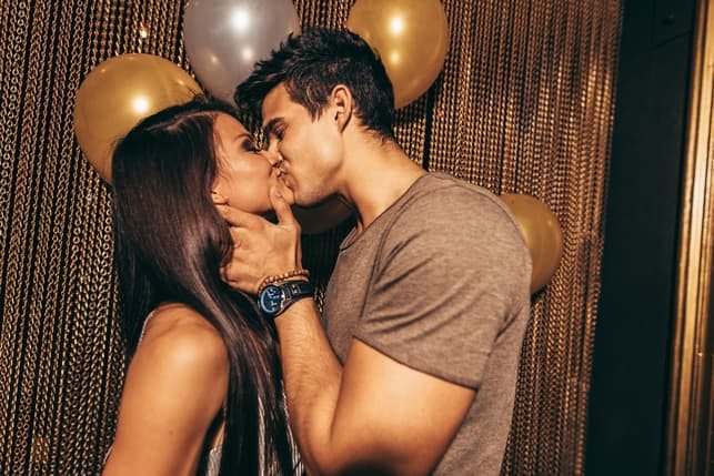 a young couple kissing at a party