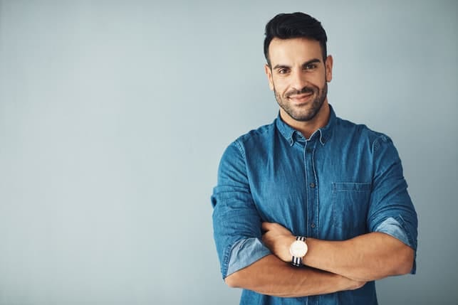 a handsome masculine man in a blue shirt posing indoors