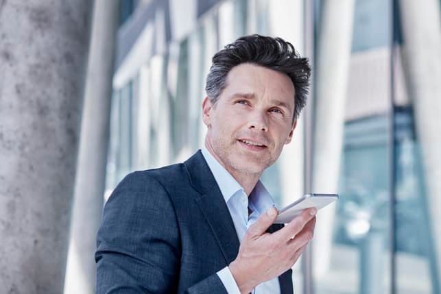 a mature man in a suit using his smartphone outside