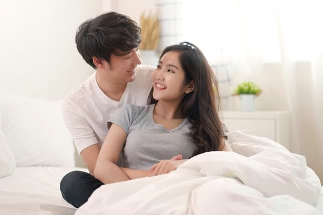 a young asian couple is cuddling and looking into each others eyes