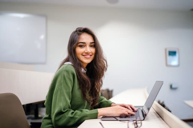 a young girl using her laptop and smiling