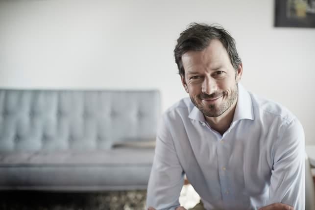 a mature man in a white shirt is smiling indoors