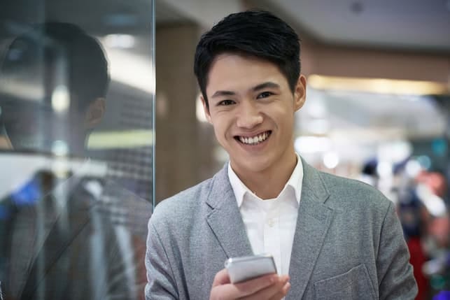a handsome asian man posing while wearing a suit