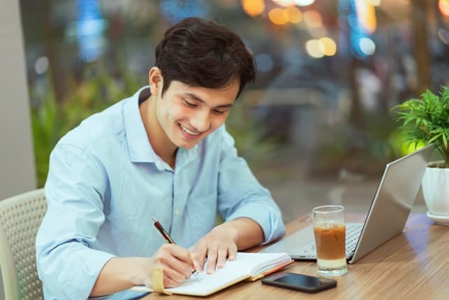 a young asian guy studying in front of his laptop