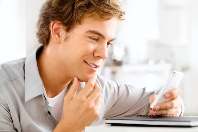 a young man is reading his messages while smiling