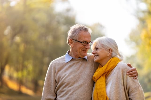 a happy senior couple is having a walk in the park