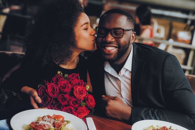 a woman kissing her boyfriend for a bouquet