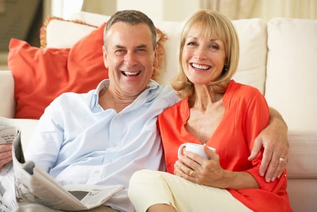 a couple over 50 is posing together at home and smiling