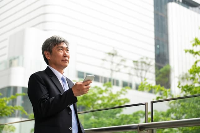 a japanese man over 50 using his smartphone outdoors