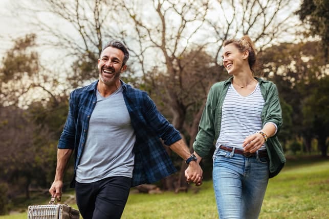 a couple is holding hands and having fun together while walking in the park