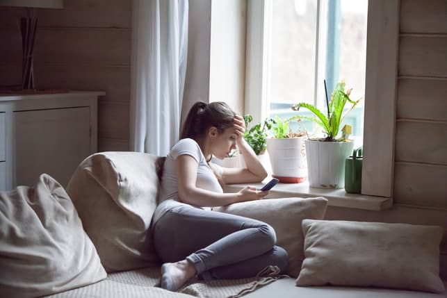 a sad woman sitting next to a window