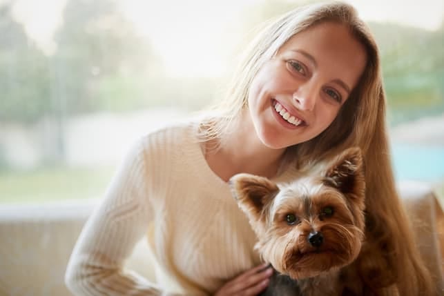 a young blonde woman is smiling and posing with her dog