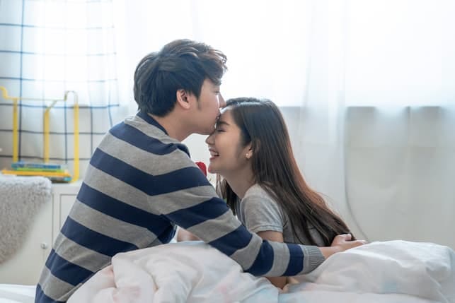 a man kissing his girlfriend’s forehead