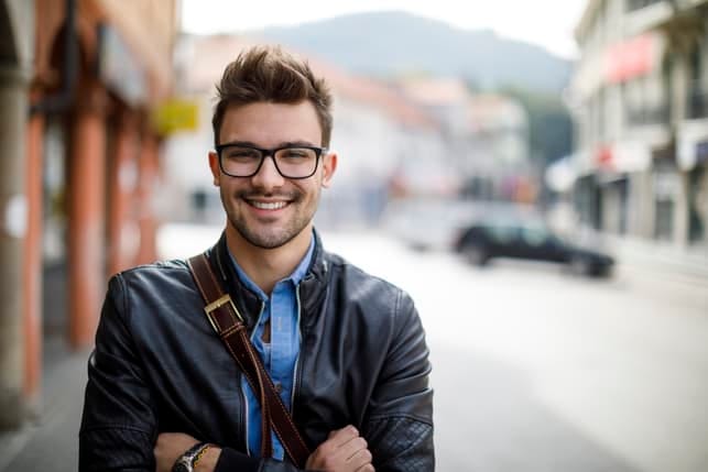 a man in glasses is smiling outdoors