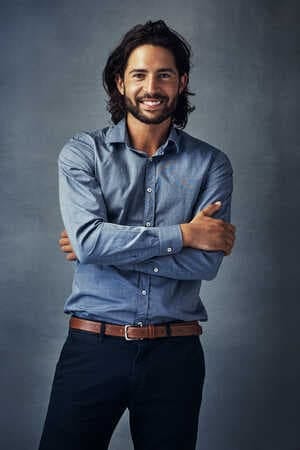 a dark-haired man in a blue shirt is smiling