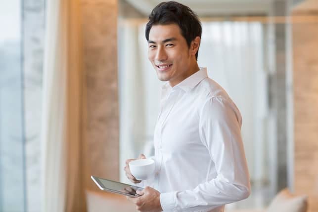 an Asian man in a white shirt posing indoors while smiling
