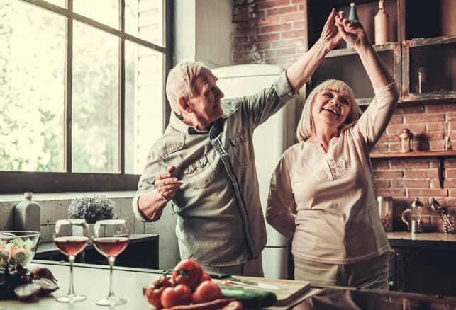 a senior couple dancing together in the kitchen