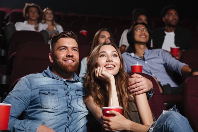 a happy young couple watching a movie at the cinema together