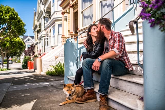 a young couple kissing while walking their dog