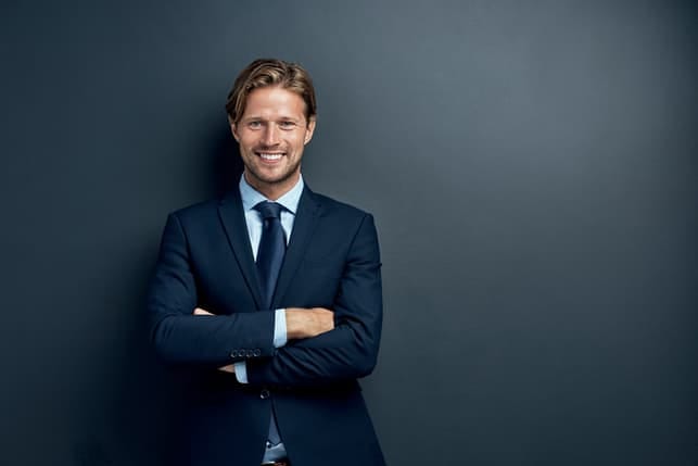 an attractive man in a suit smiling and posing indoors
