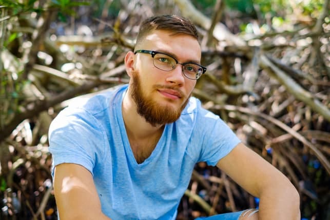 a portrait of a young bearded man wearing glasses