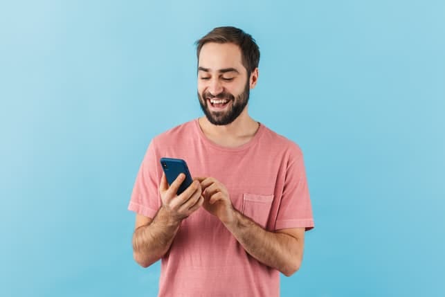 a man reading his messages while smiling happily