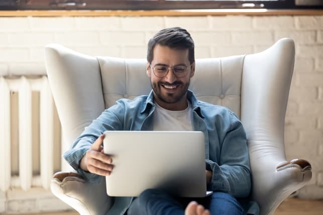 a handsome middle-aged man is using his laptop while smiling