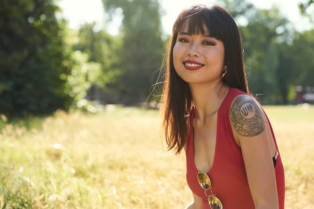 an attractive asian woman with a fringe is smiling outdoors