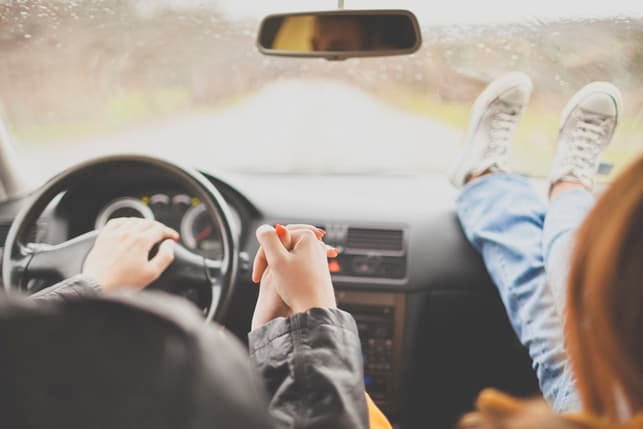 a couple driving while holding hands